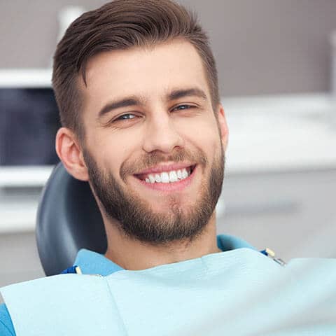 Mann mit strahlend weißem Lachen während eines Zahnarztbesuchs